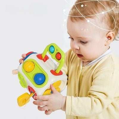 Bébé manipulant un cube d’activité Montessori sensoriel, busy cube 9 en 1 pour développer la motricité fine, la coordination main-œil et la logique dès 1 an