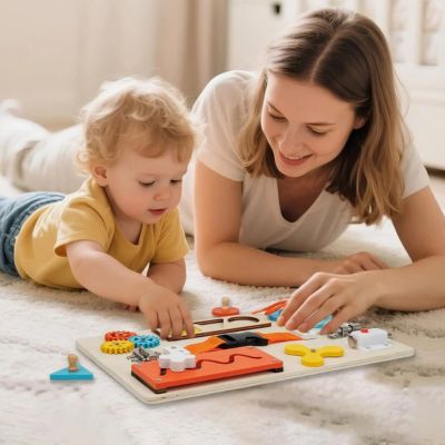 Maman jouant avec son enfant sur une planche d’activité Montessori en bois, busy board éducatif pour développer motricité fine et autonomie dès 3 ans.