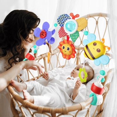 Parent interagissant avec un bébé sous un arc d’activité installé sur un berceau, jouets sensoriels favorisant l’éveil et la coordination dès la naissance