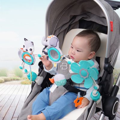 Bébé installé dans une poussette jouant avec un arc d’activité doté de jouets sensoriels colorés, favorisant l’éveil, la motricité et l’attention en déplacement