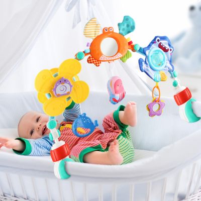 Bébé allongé jouant avec un arc d’activité pour poussette composé de jouets sensoriels colorés, favorisant l’éveil, la motricité fine et la coordination