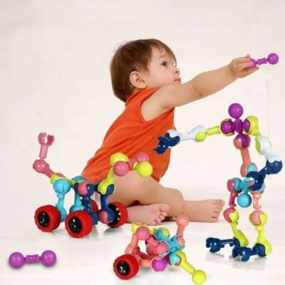 Bébé jouant avec des blocs de construction articulés STEM pour créer des formes et véhicules colorés, jeu d’éveil favorisant la motricité fine et la créativité