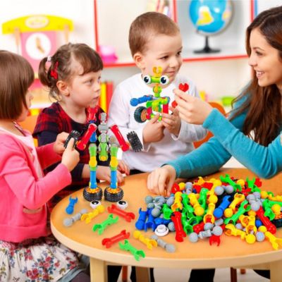 Groupe d’enfants jouant ensemble avec des blocs de construction articulés STEM, activité éducative favorisant la créativité, la coopération et le développement moteur
