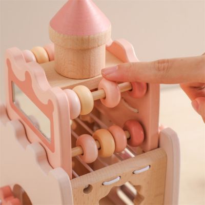 Gros plan sur les perles coulissantes du château Montessori en bois, activité de motricité fine et coordination pour bébé