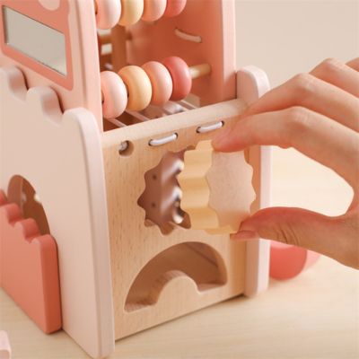 Enfant manipulant une pièce en forme d’engrenage sur un château Montessori en bois, jouet éducatif de tri de formes et motricité fine