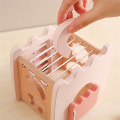 Main d’adulte insérant une pièce en forme de lune dans le château Montessori en bois, jeu de tri de formes et développement de la motricité fine