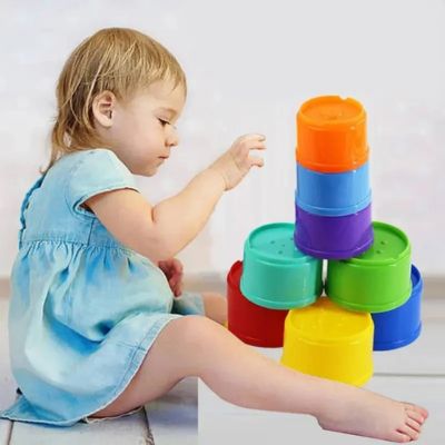 Bébé jouant avec des gobelets empilables Montessori colorés, jouet éducatif favorisant la motricité fine, la coordination et l’apprentissage des couleurs
