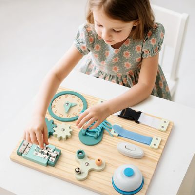 Enfant concentré manipulant une planche d’activité Montessori en bois avec lacet, engrenages et interrupteurs, jouet éducatif favorisant la motricité fine et l’apprentissage autonome
